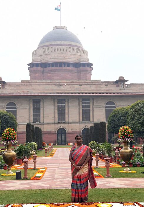 President Droupadi Murmu in the gardens of Rashtrapati Bhavan with the dome of the building behind her