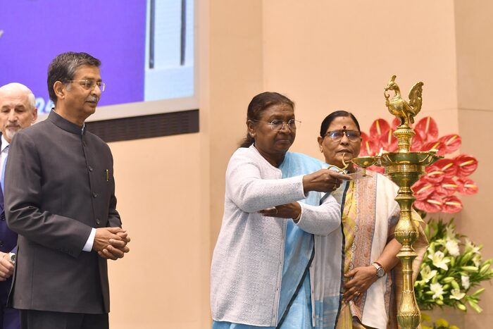 President Droupadi Murmu lighting a tall brass ceremonial lamp at an official function