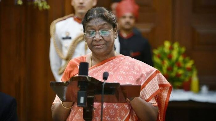 President Droupadi Murmu speaking at a lectern with microphones at a formal state occasion