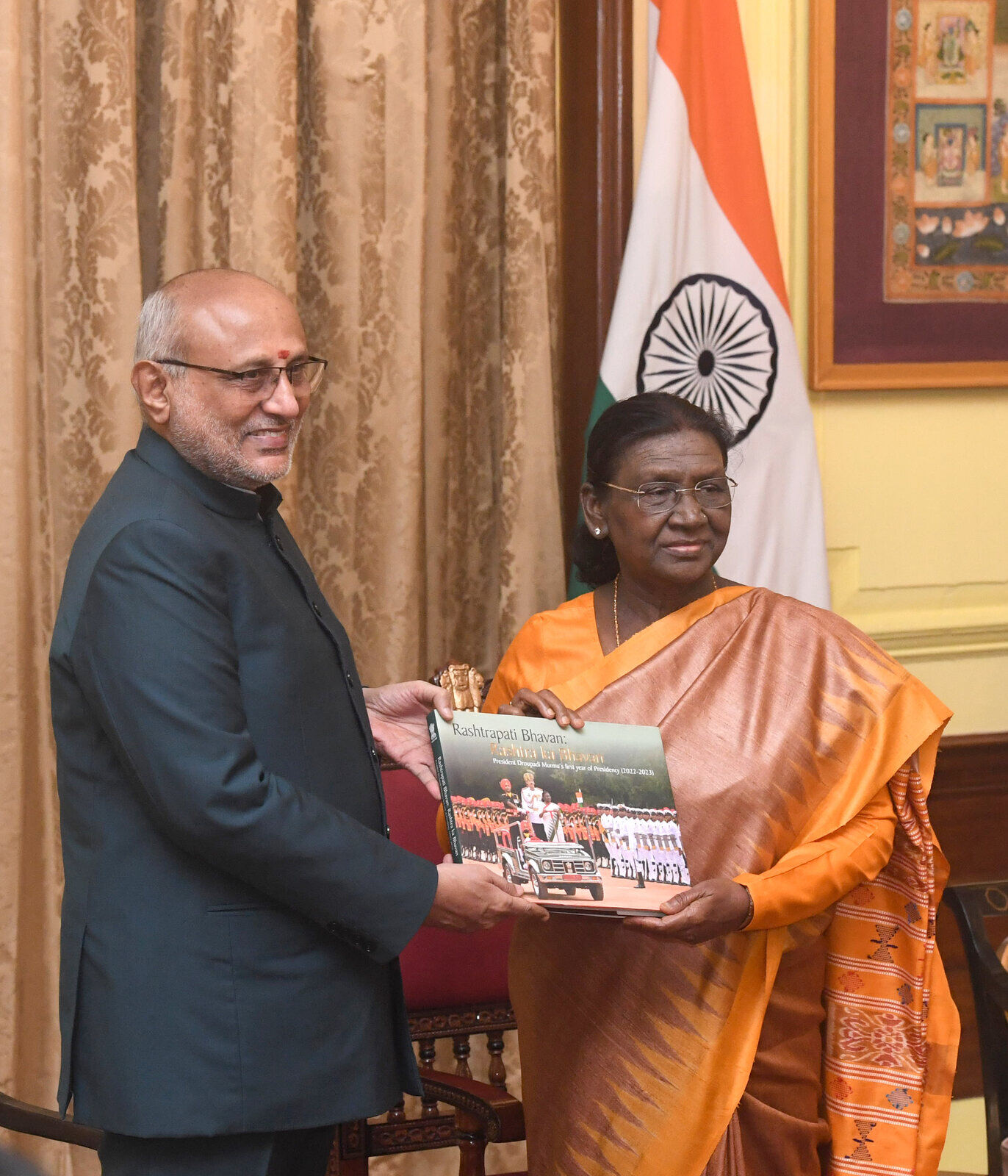 President Droupadi Murmu receiving a bound volume documenting Rashtrapati Bhavan, presented by an official