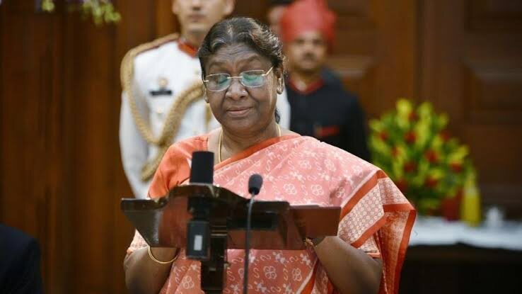 President Droupadi Murmu speaking at a lectern with microphones at a formal state occasion